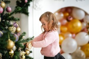 Caucasian blond child with Down syndrome in front of Christmas tree By natalialeb